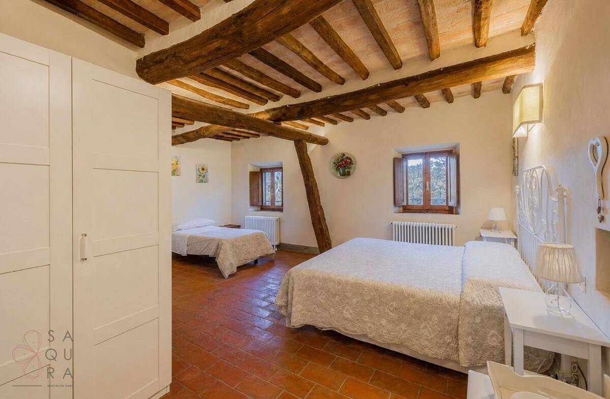 Geräumiges Schlafzimmer mit Terrakottaboden, Holzbalkendecke und weißem Kleiderschrank.