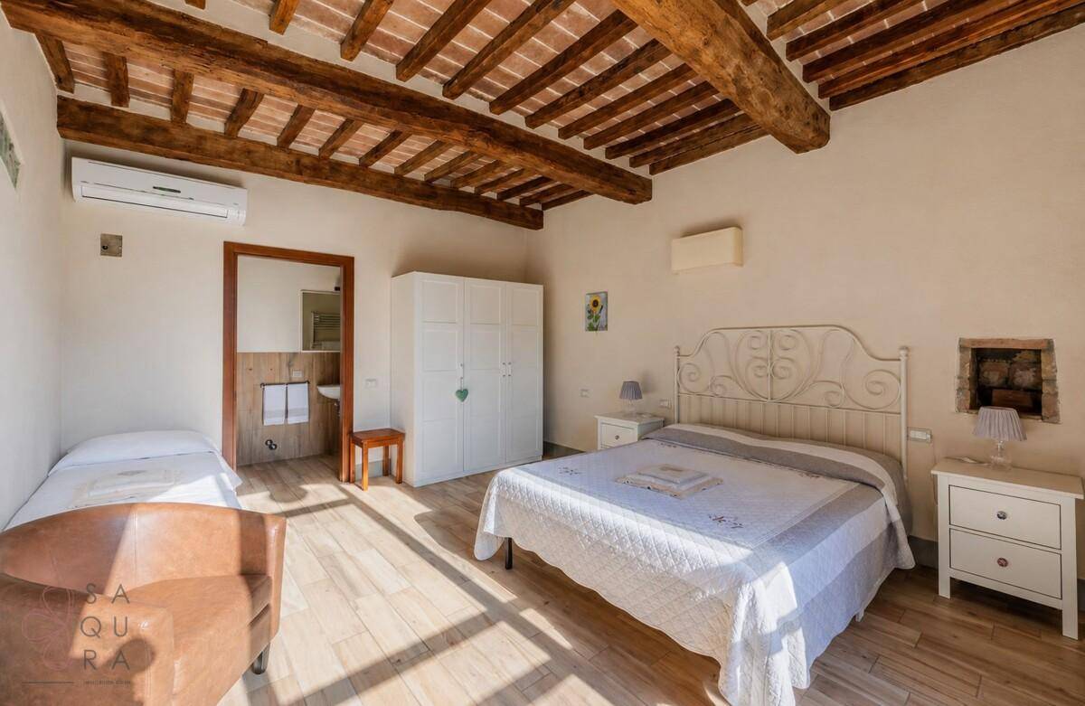 Helles Schlafzimmer mit Holzbalkendecke, Klimaanlage und angrenzendem Badezimmer.