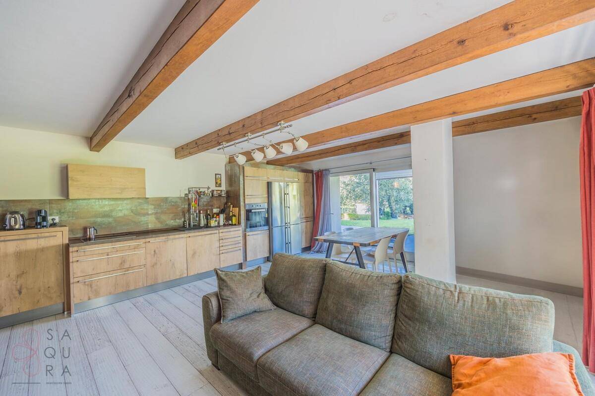 Moderne Holzküche und Wohnbereich mit Sofa, Holzbalken und Zugang zum Garten.