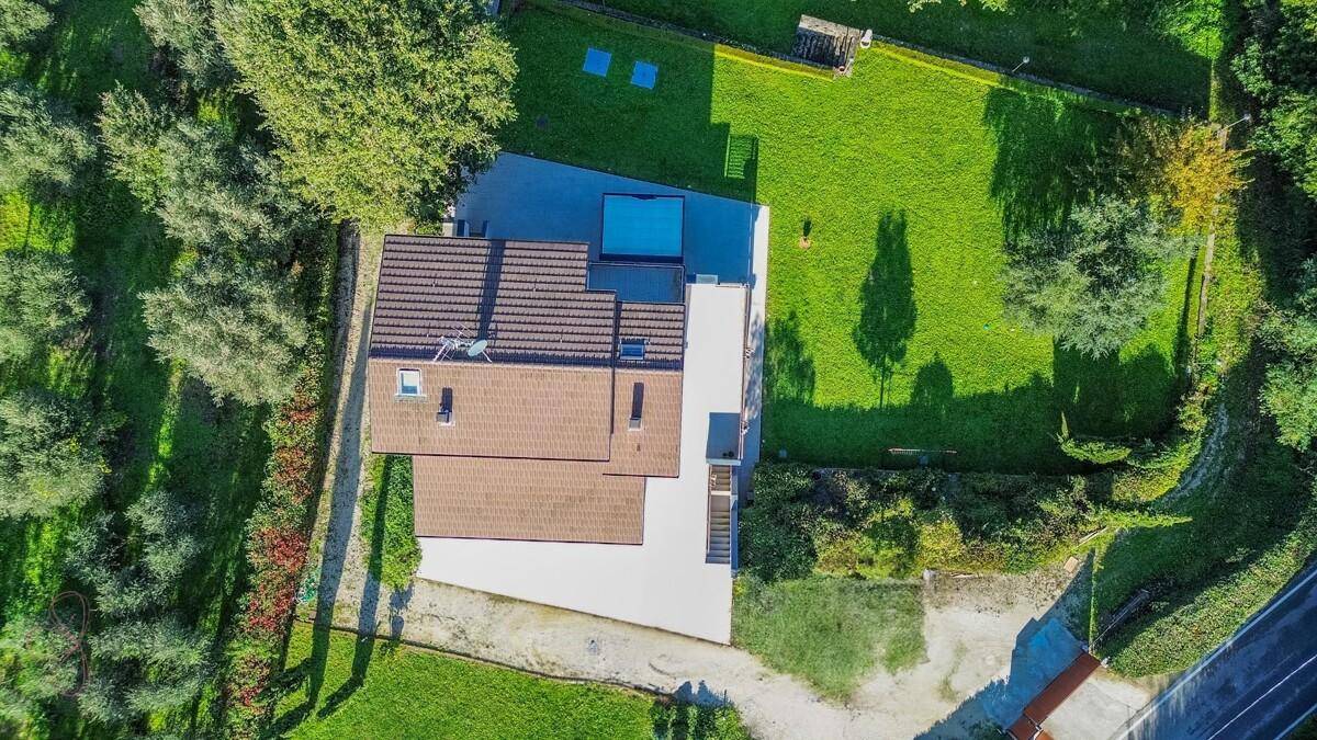 Draufsicht auf das Haus mit Dach, Garten und gepflasterten Flächen.