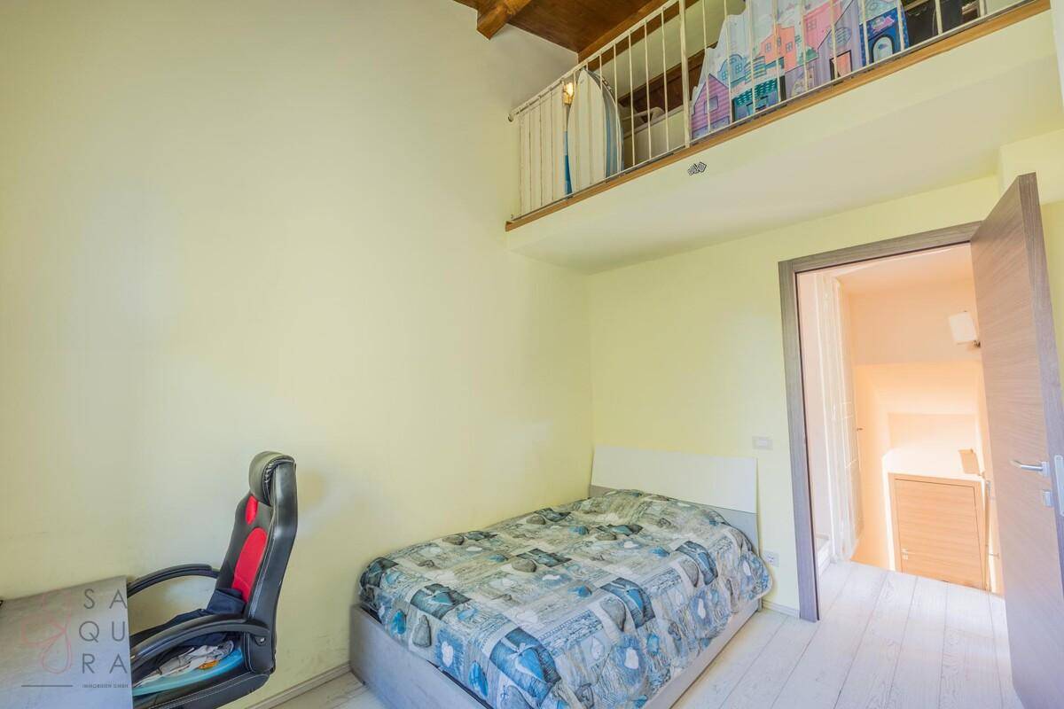 Kinderzimmer mit hoher Decke, Holzbalken und einer kleinen Galerie oder einem Hochbettbereich.