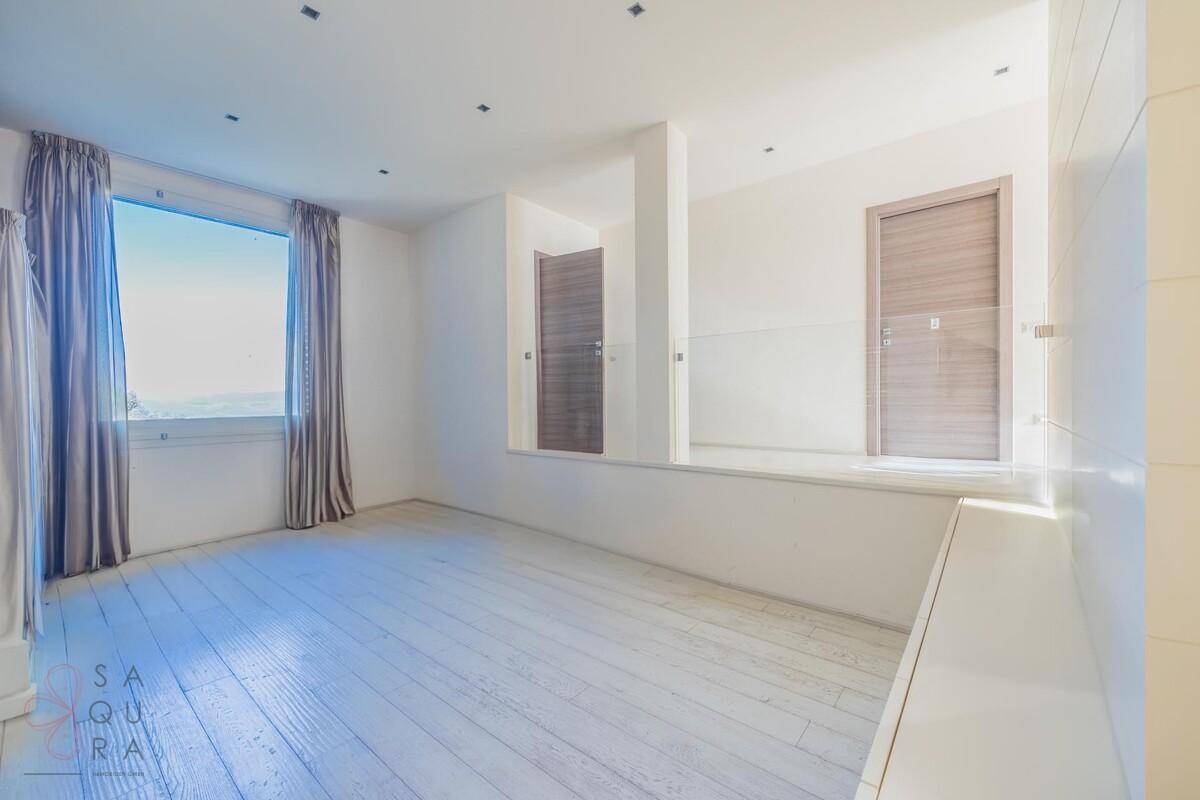 Heller, offener Raum mit weiß gestrichenem Holzboden und großem Fenster, das viel Tageslicht hereinlässt.