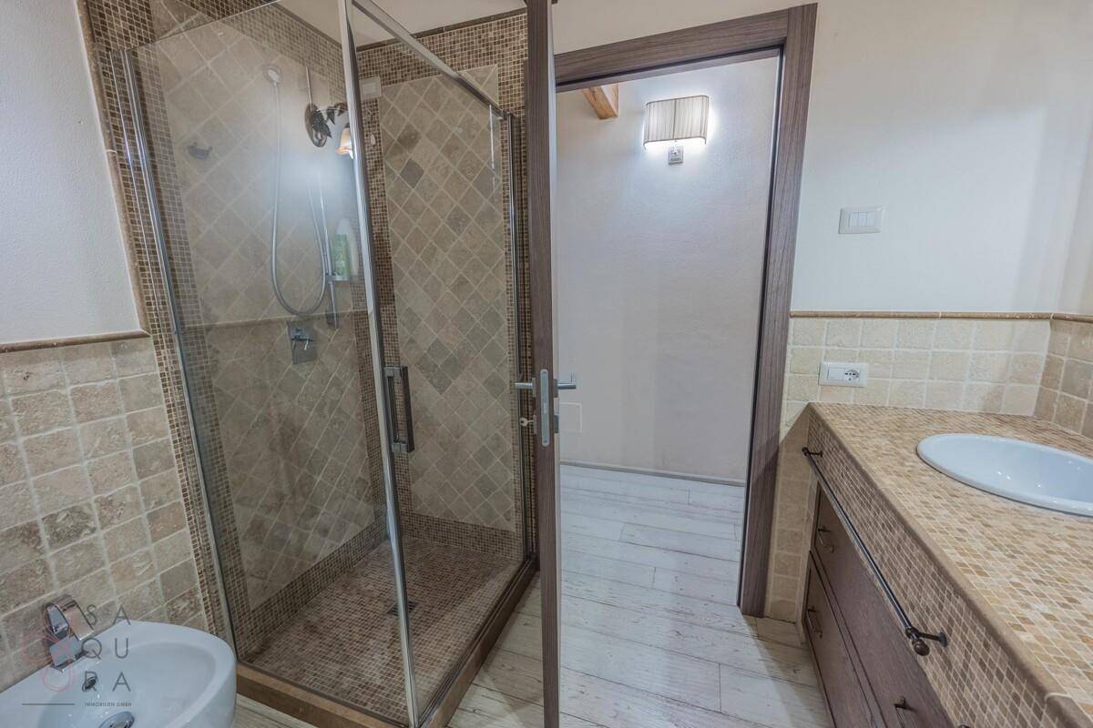 Badezimmer mit begehbarer Dusche, Bidet und gefliesten Wänden in warmen Erdtönen.