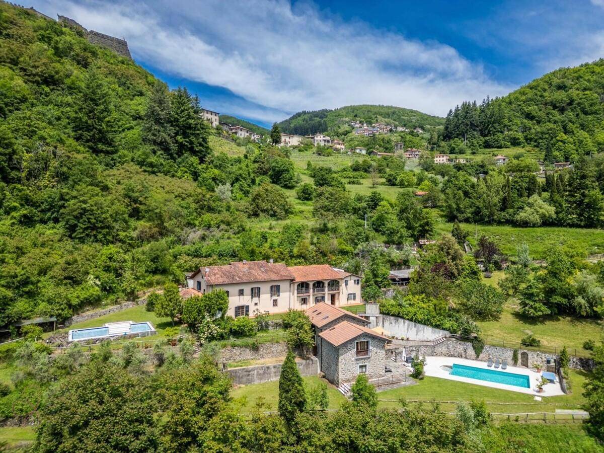 Idyllisches Anwesen in den Bergen mit zwei Pools und weitläufigen Grünflächen unter blauem Himmel.
