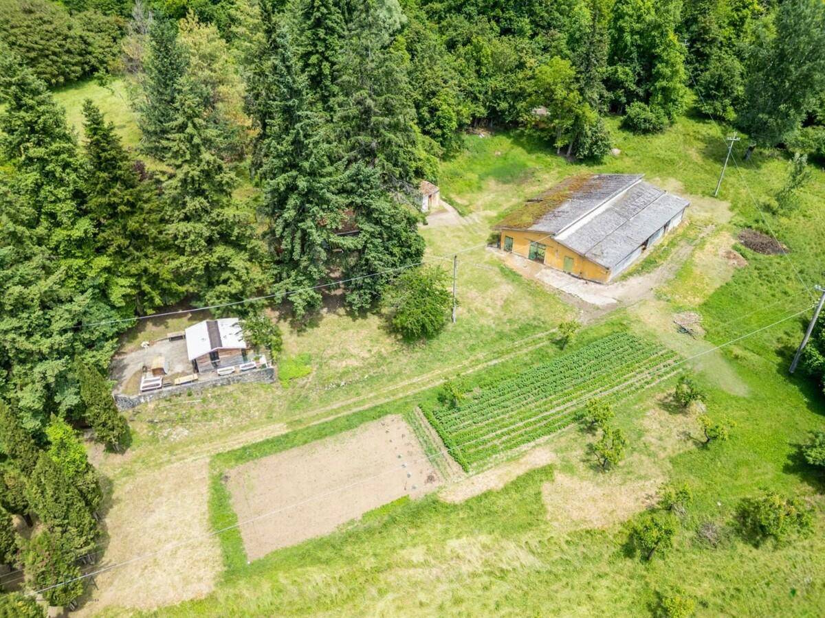 Luftaufnahme eines landwirtschaftlichen Bereichs mit Scheune, Schuppen und angelegten Gemüsebeeten.