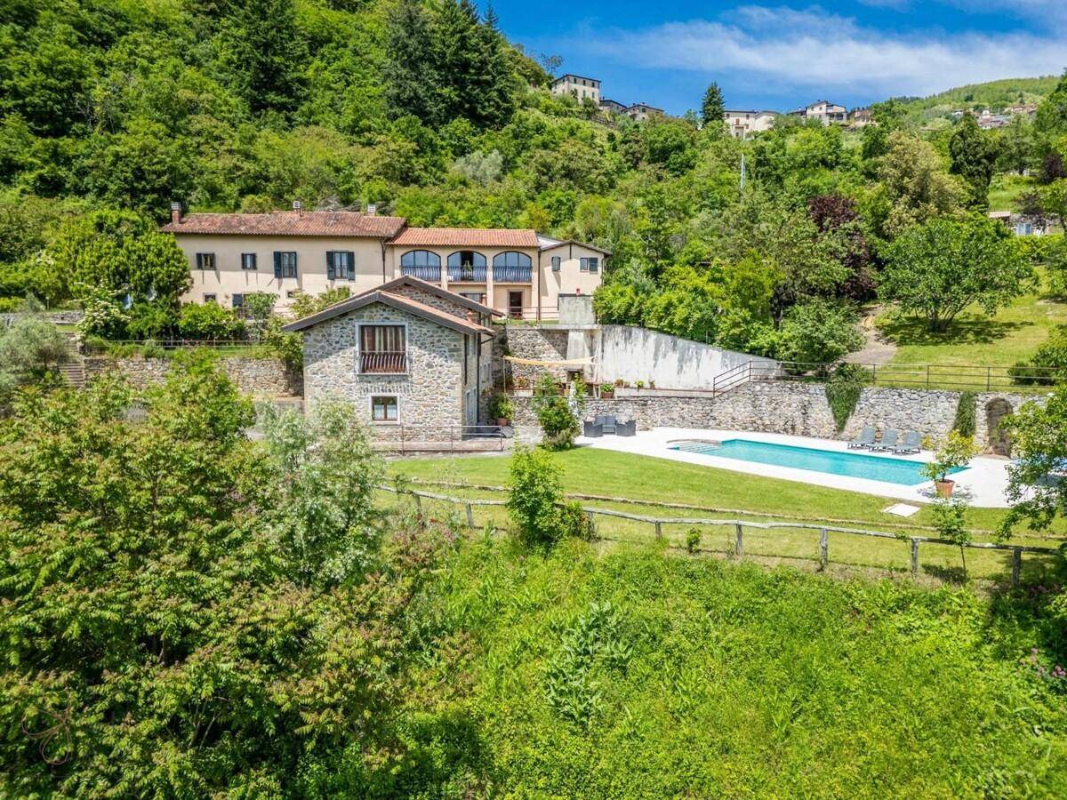 Anwesen mit traditionellen Gebäuden und einem Pool, eingebettet in eine üppige grüne Landschaft.