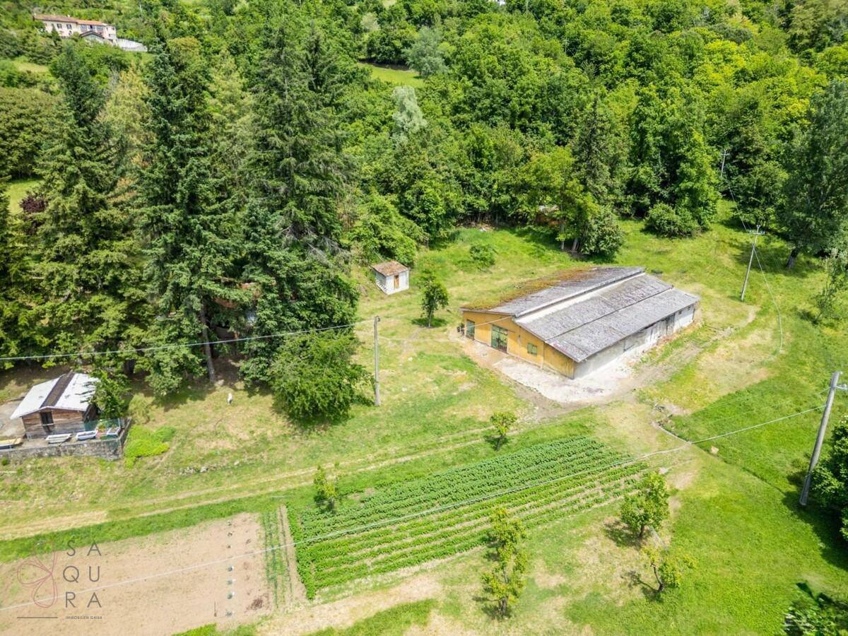 Luftaufnahme des landwirtschaftlichen Bereichs mit Scheune, Schuppen und angelegten Gemüsebeeten.