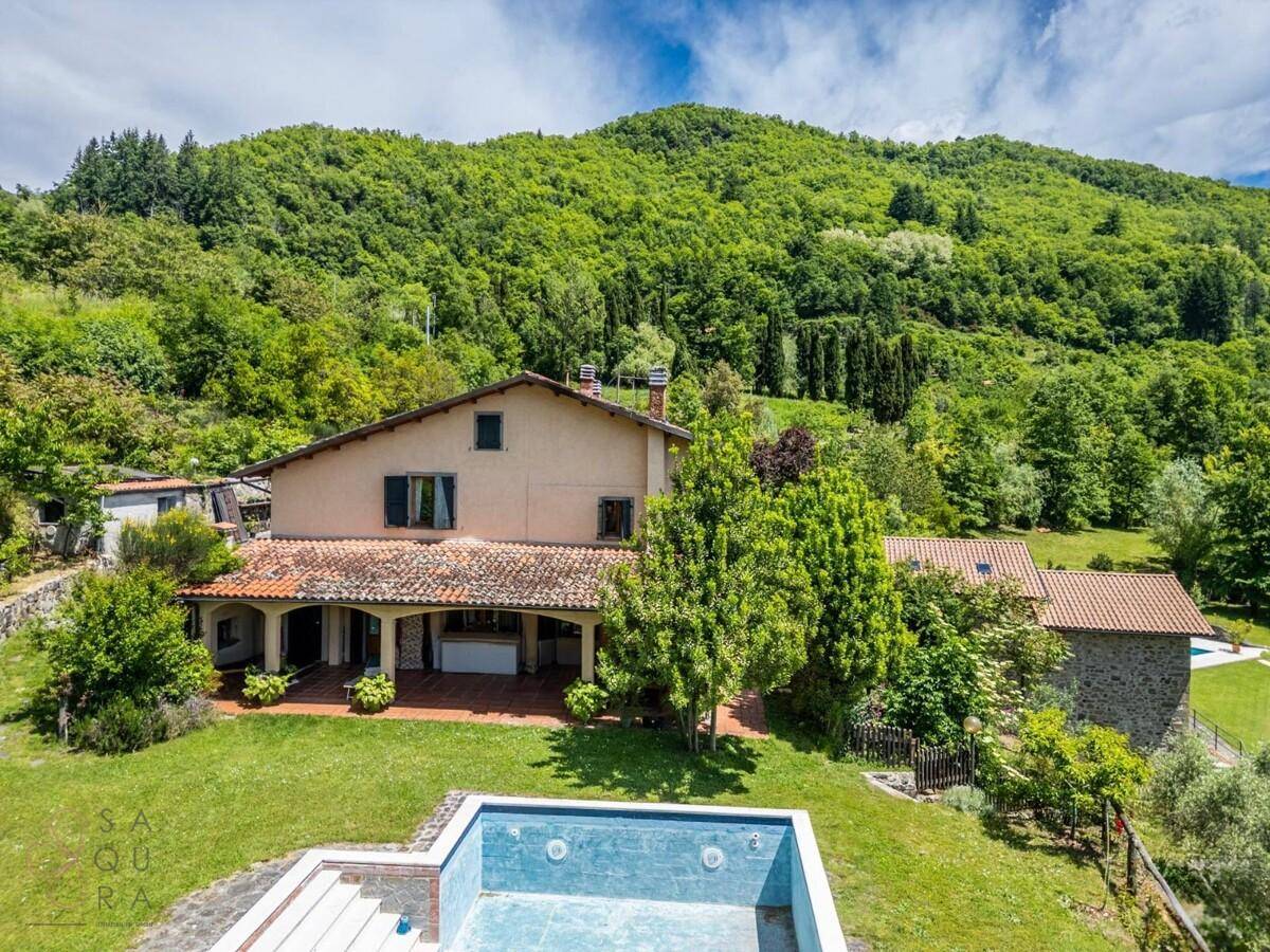 Nahaufnahme des Hauptgebäudes mit überdachter Terrasse und einem leeren Swimmingpool im Vordergrund.