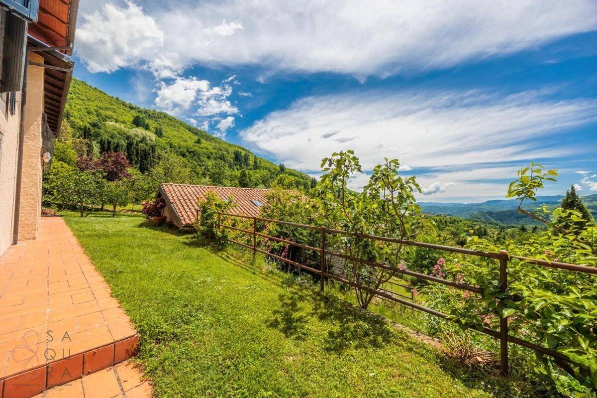 Grüne Rasenfläche neben dem Haus mit weitem Blick über die hügelige Landschaft.
