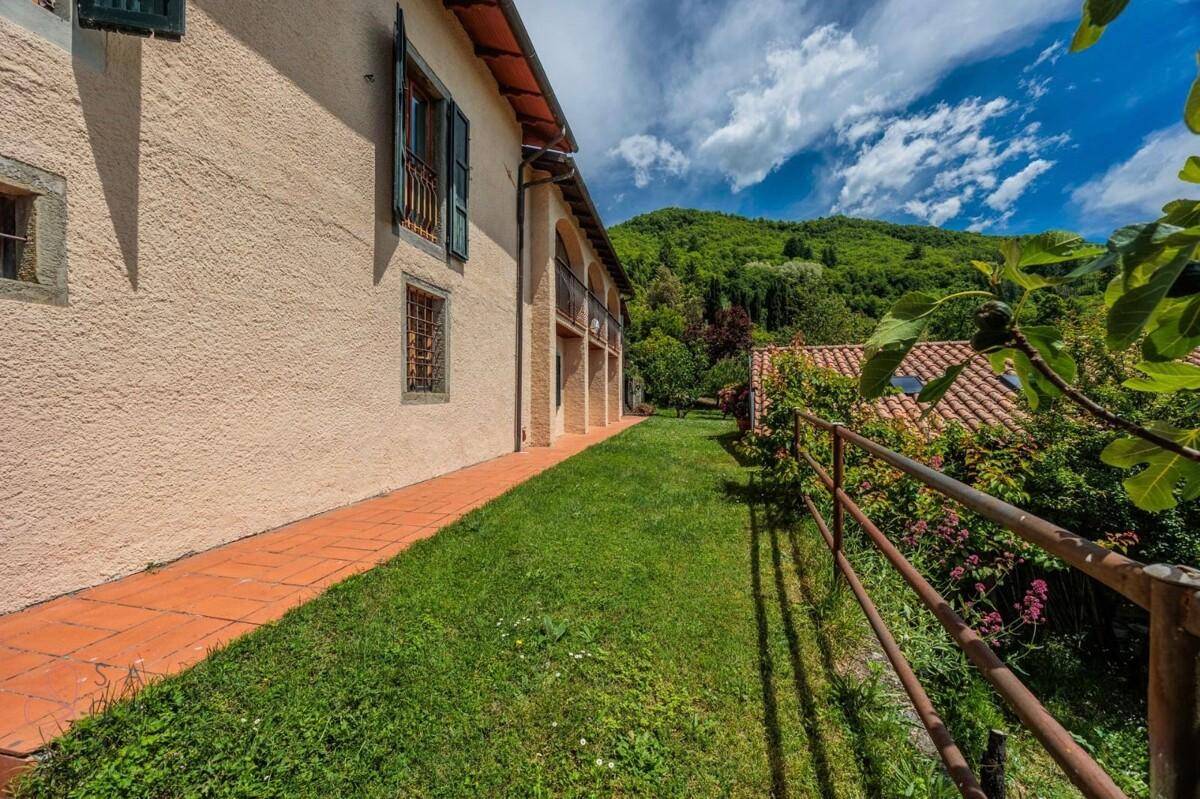 Seitenansicht des Hauses mit Rasenfläche und Blick auf die umliegende grüne Landschaft.