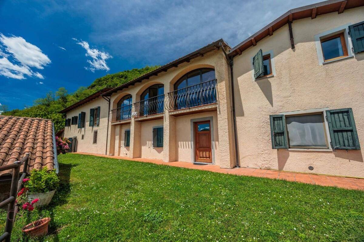Ansicht der Hausfassade mit Balkonen und Fenstern, umgeben von einer grünen Wiese.
