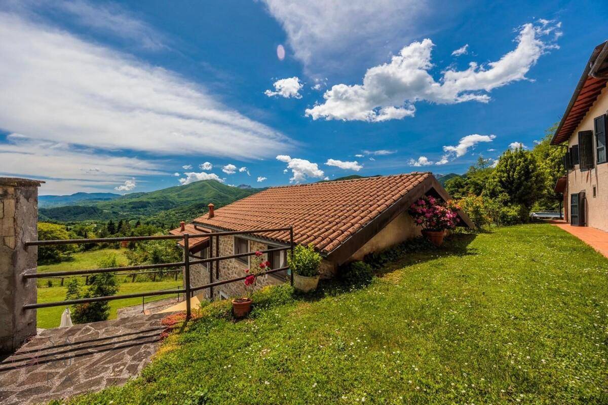Gebäude mit Ziegeldach und weitem Blick über die grüne Hügellandschaft.