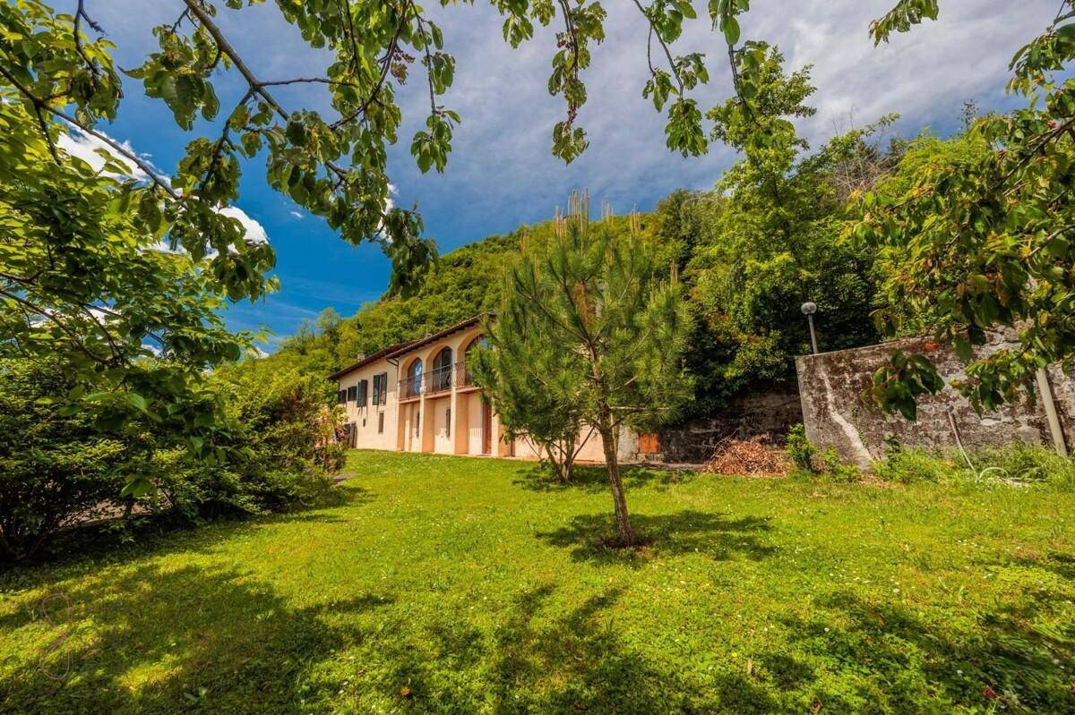 Weitläufiger Garten mit üppigem Grün, Bäumen und dem Haus im Hintergrund.