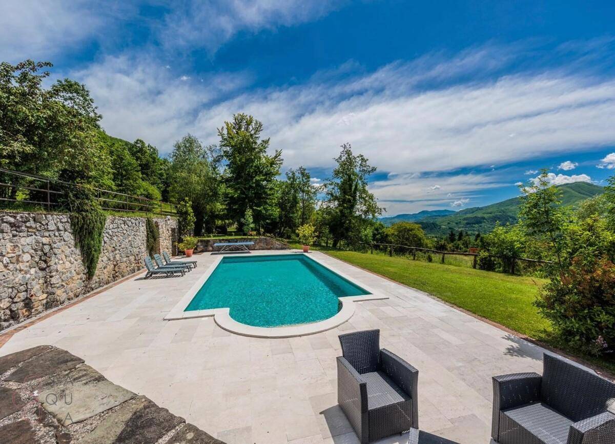Weitläufiger Poolbereich mit Sitzgelegenheiten und atemberaubendem Blick auf die Berglandschaft.