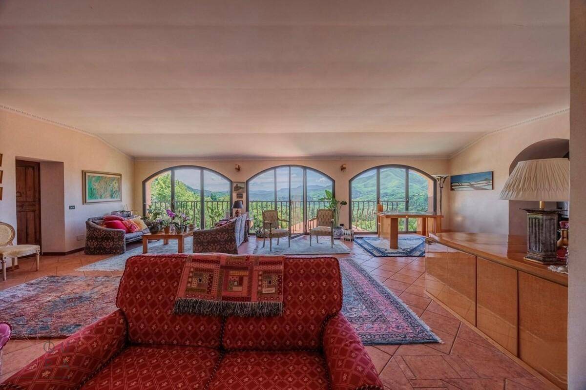 Geräumiges Wohnzimmer mit großen Bogenfenstern, die einen weiten Blick auf die Landschaft bieten.