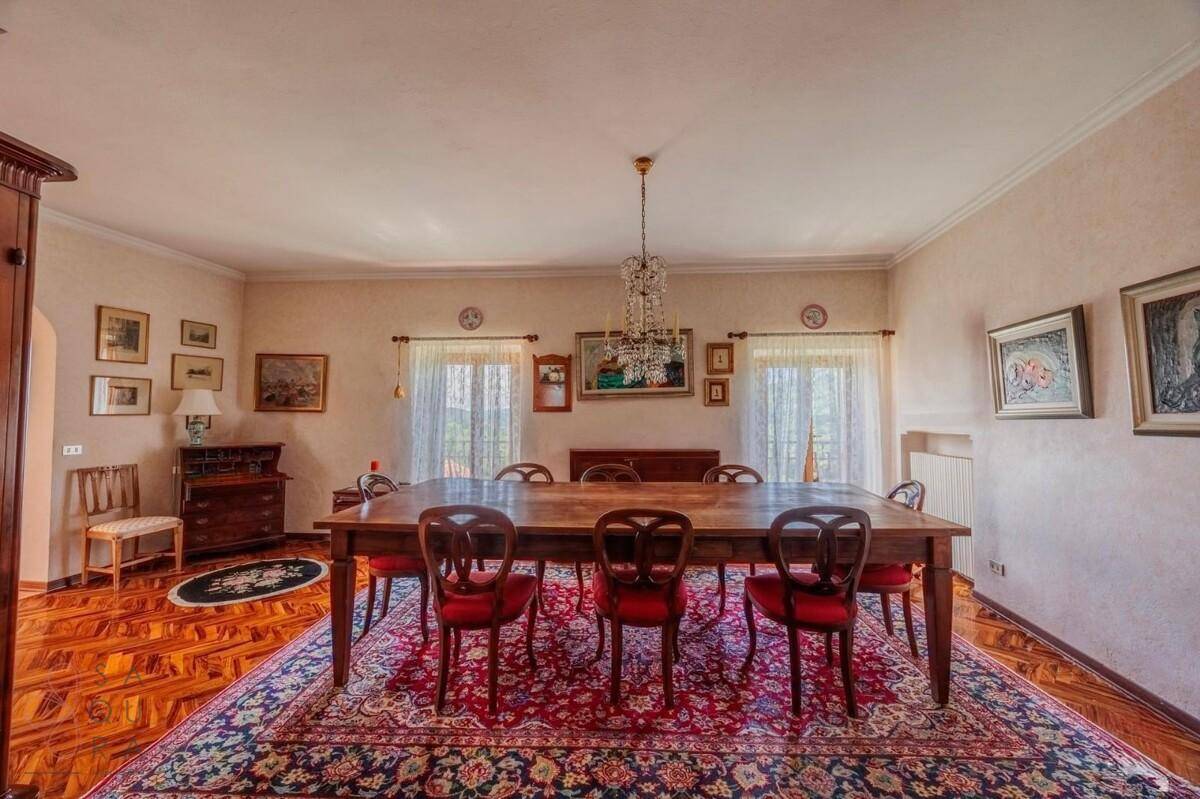 Klassisches Esszimmer mit einem großen Holztisch, roten Stühlen und einem eleganten Kronleuchter.