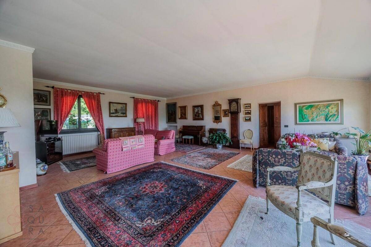 Großes Wohnzimmer mit verschiedenen Sitzbereichen, klassischen Möbeln und farbenfrohen Teppichen.