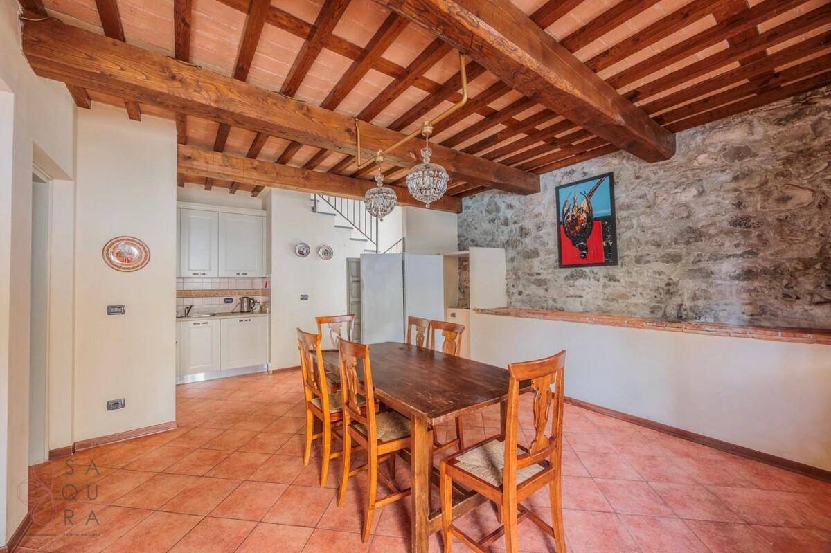 Rustikaler Essbereich mit Holzbalkendecke, Steinwand und einer kleinen, funktionalen Küchenzeile.