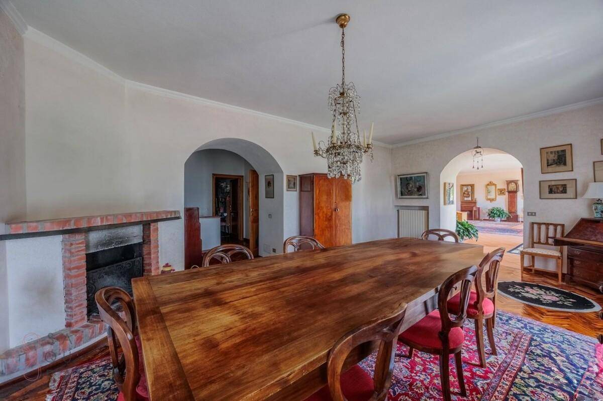 Geräumiges Esszimmer mit einem gemauerten Kamin und eleganten Rundbögen, die zu weiteren Räumen führen.