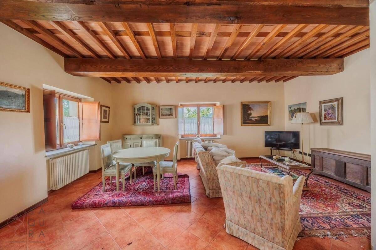 Wohnzimmer mit sichtbaren Holzbalken, traditionellen Möbeln und einem runden Esstisch.