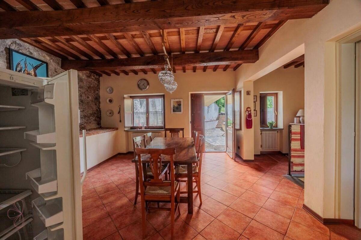 Rustikaler Essbereich mit Holzbalkendecke, Steinwand und großem Kühlschrank.