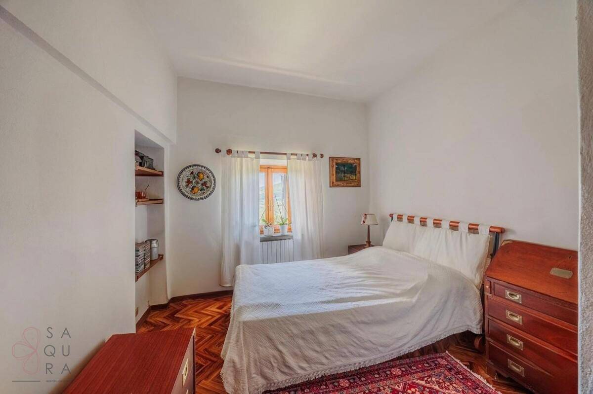 Helles Schlafzimmer mit Holzboden, einem Einzelbett und praktischen Einbauregalen neben dem Fenster.