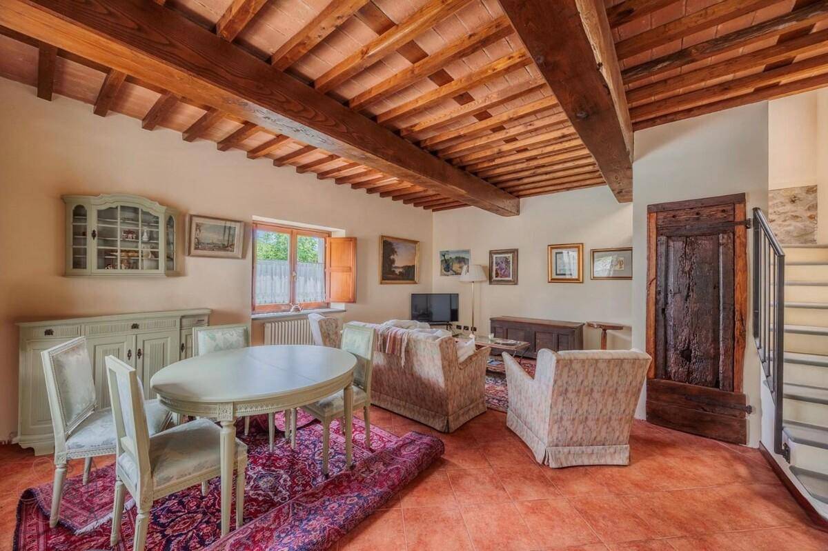 Wohnzimmer mit Holzbalkendecke, traditioneller Einrichtung und einer Treppe.