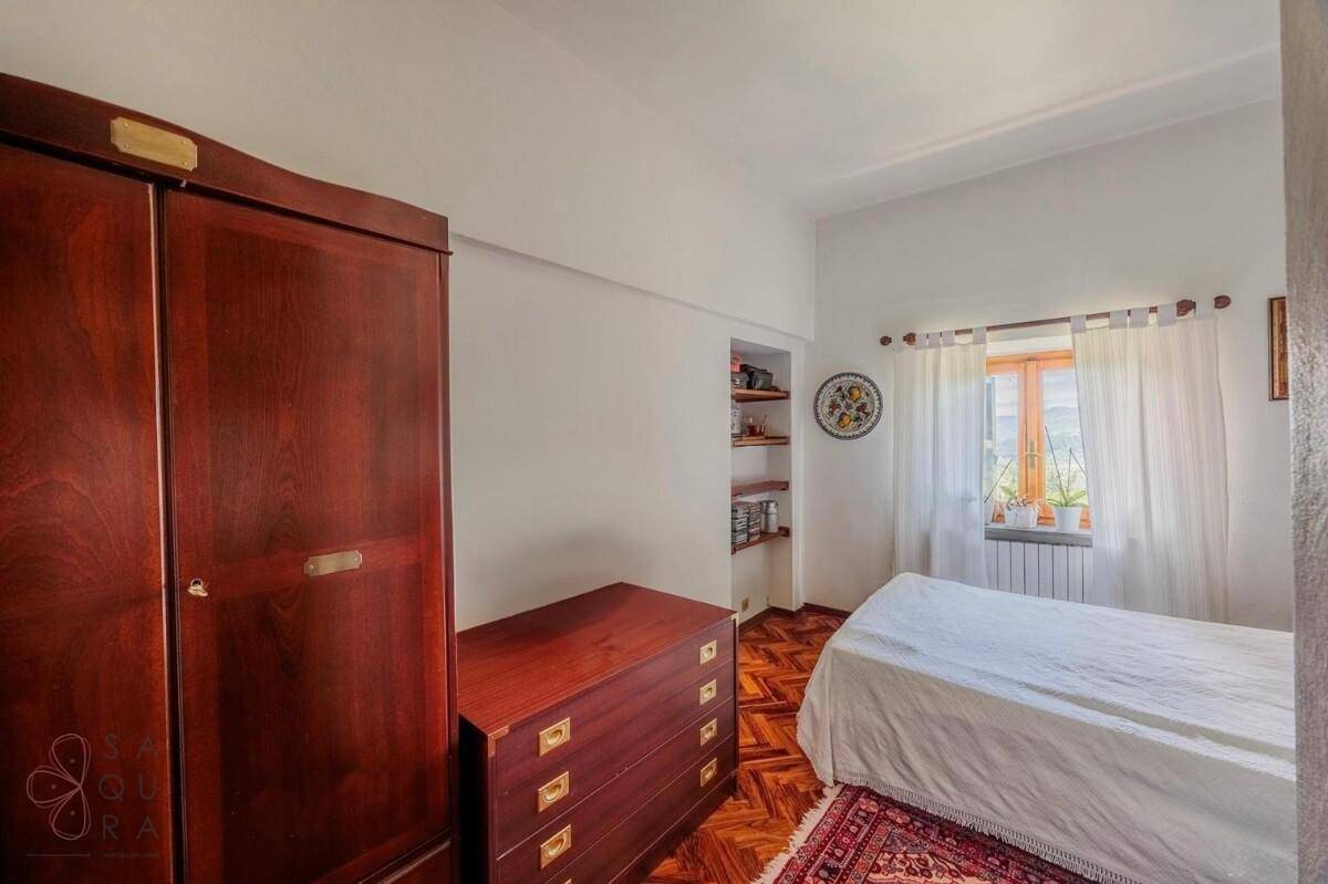 Gemütliches Schlafzimmer mit klassischem Holzmobiliar, Parkettboden und einem Fenster mit Tageslicht.