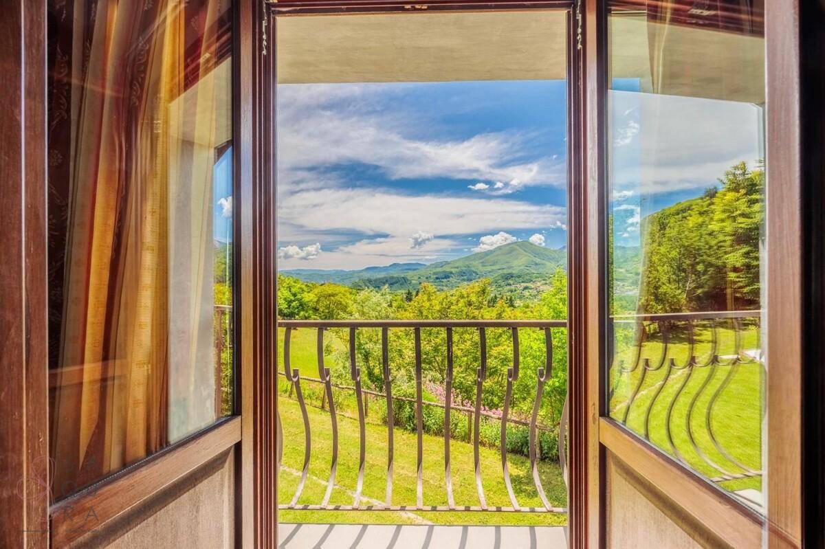 Atemberaubender Blick von einem französischen Balkon auf die umliegende Berglandschaft und viel Grün.