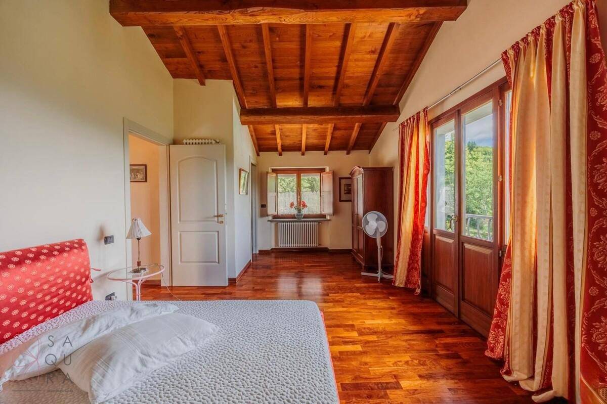 Helles Schlafzimmer mit Holzbalkendecke, Holzboden und einem französischen Balkon mit schöner Aussicht.