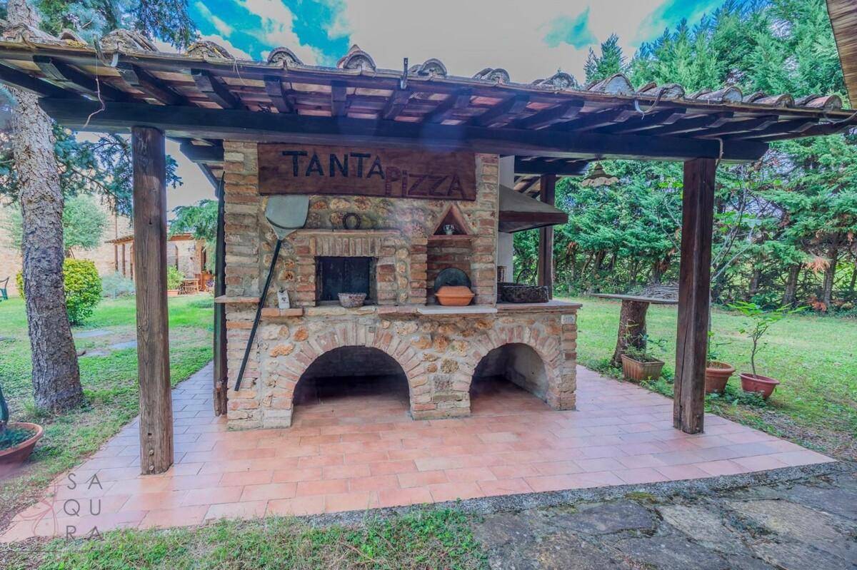 Traditioneller gemauerter Pizzaofen mit Holzdach und rustikalem Charme im Gartenbereich.
