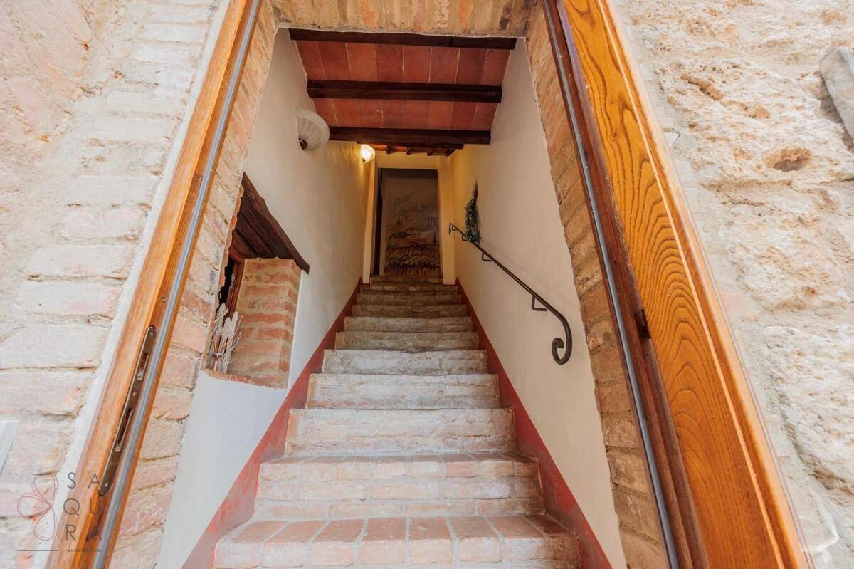 Steintreppe mit schmiedeeisernem Geländer, umgeben von rustikalen Ziegel- und Steinwänden.