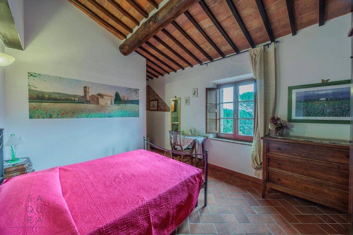 Helles Schlafzimmer mit Terrakottaboden, Holzbalkendecke und Fenster mit Blick ins Grüne.