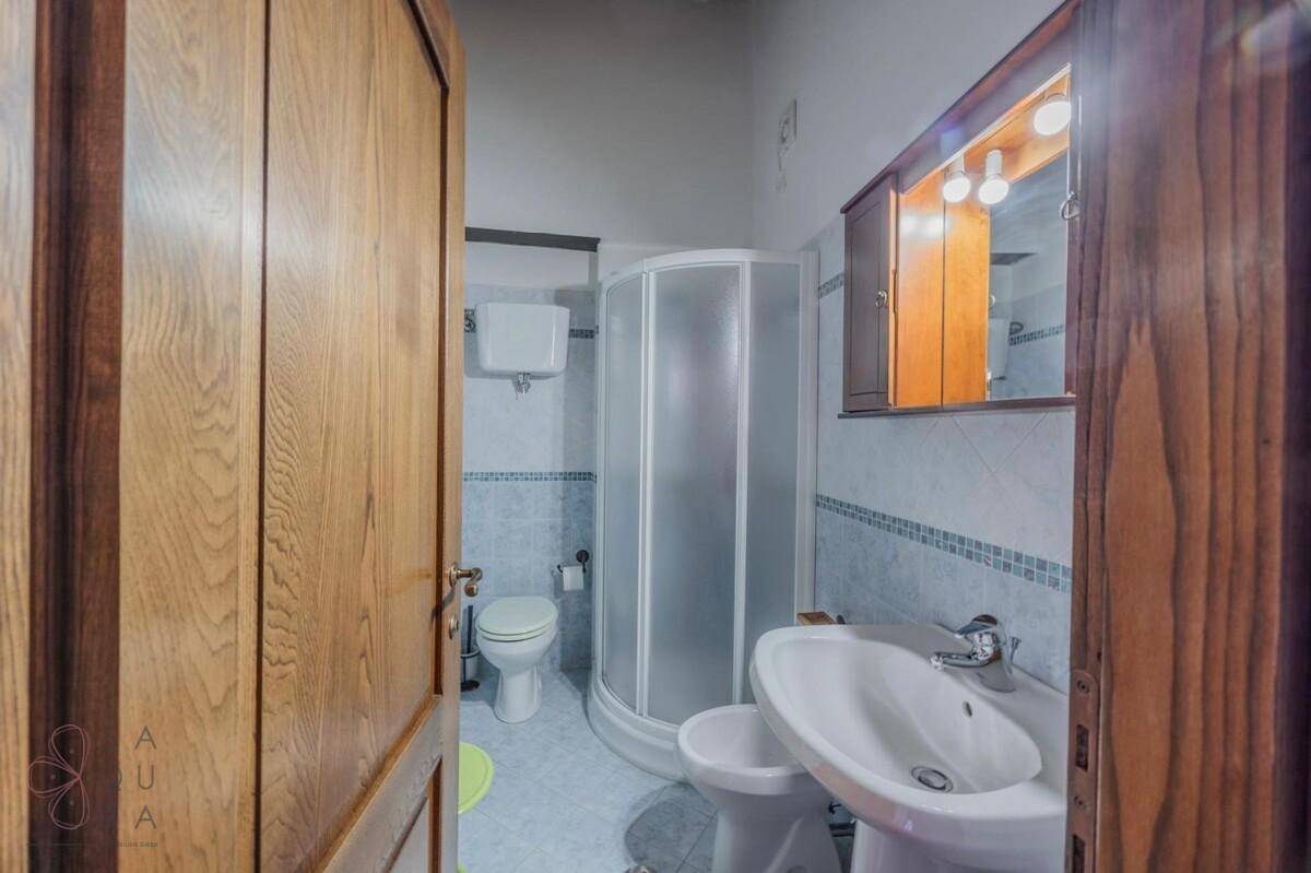 Kleines Badezimmer mit Duschkabine, WC und Waschbecken in hellem Holzdesign.