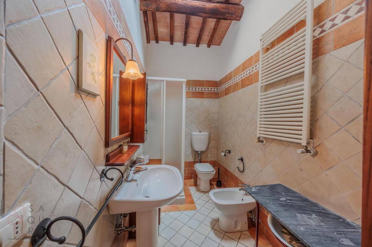 Geräumiges Badezimmer mit Fliesen, Duschkabine, WC, Bidet und beheiztem Handtuchhalter.
