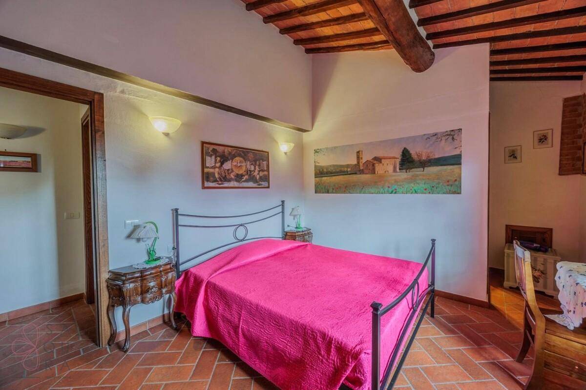 Gemütliches Schlafzimmer mit Terrakottaboden, Holzbalkendecke und traditioneller Einrichtung.