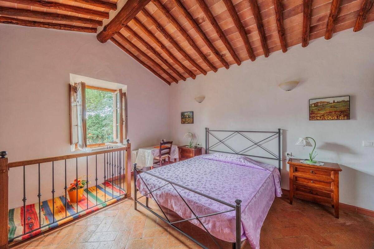 Rustikales Schlafzimmer mit Terrakottaboden, Holzbalkendecke und einem Fenster mit Ausblick.