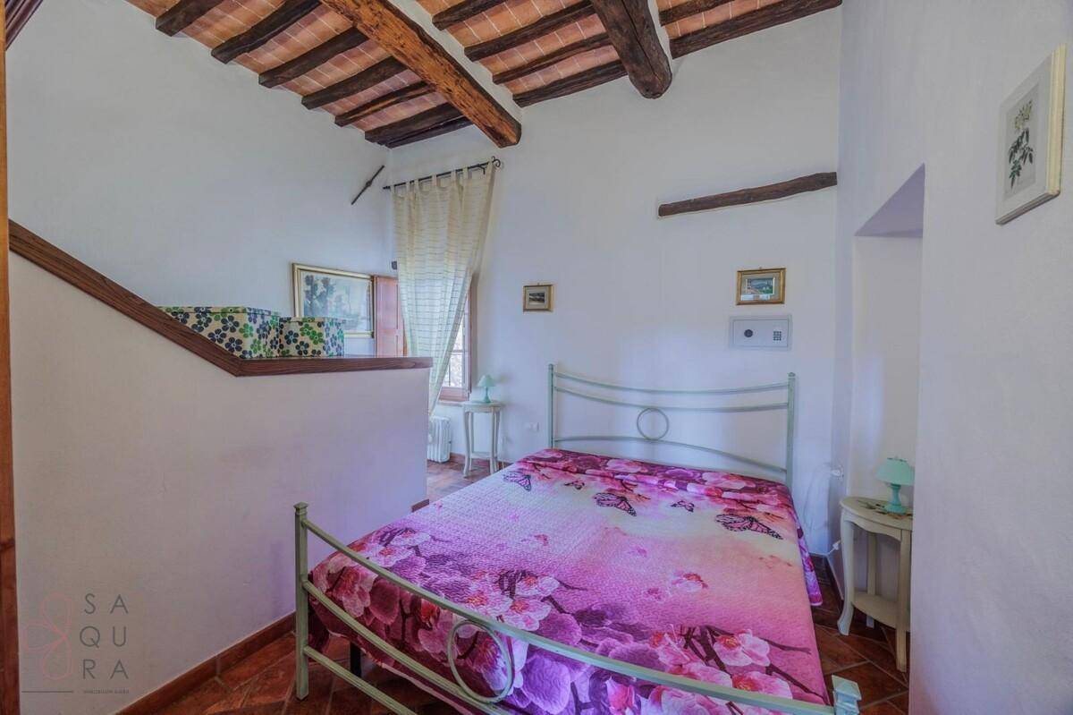 Schlafzimmer mit Doppelbett, kleinem Tisch und Fenster, mit rustikalem Terrakottaboden.