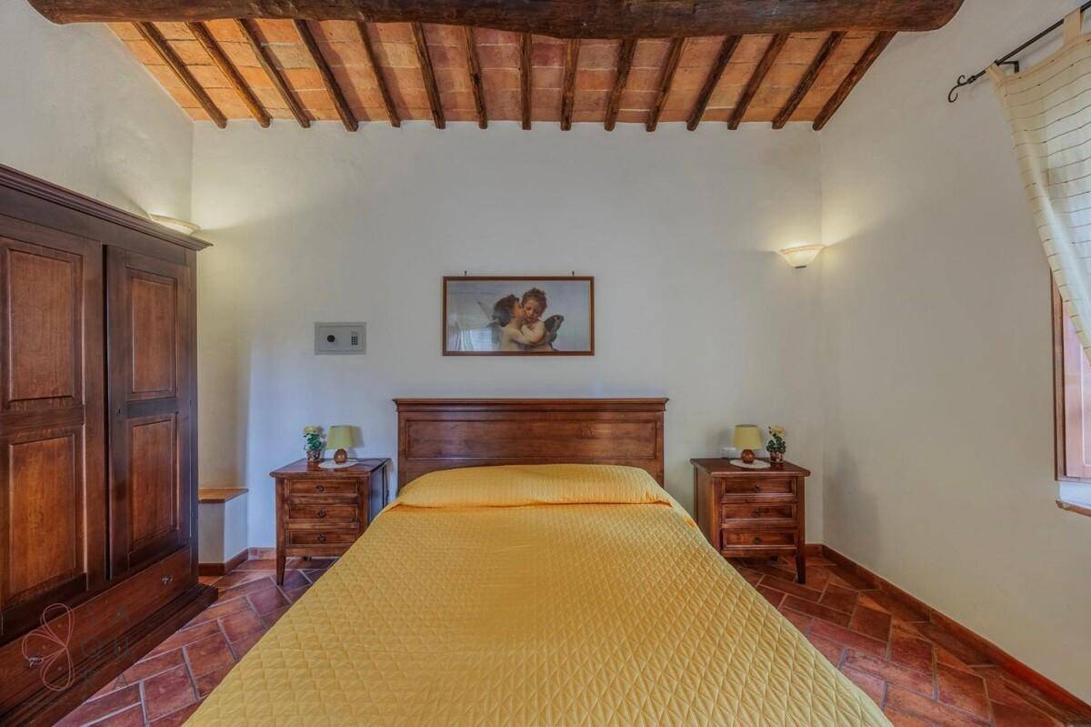 Schlafzimmer mit Doppelbett, Nachttischen und Kleiderschrank, unter sichtbaren Holzbalken.