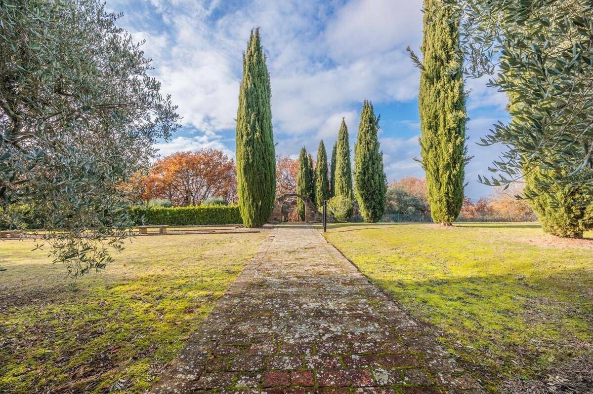 Langer Ziegelweg, gesäumt von hohen Zypressen, führt durch den weitläufigen Garten.