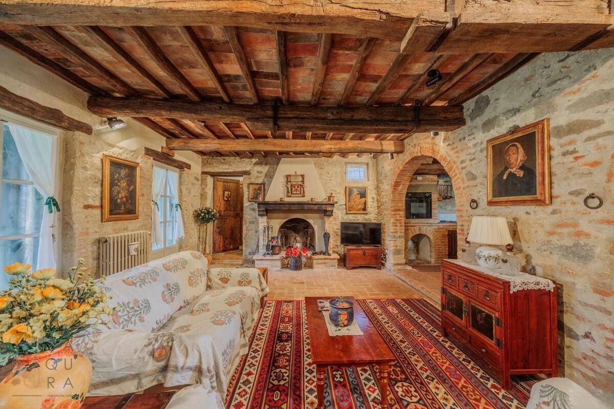 Geräumiges Wohnzimmer mit Kamin, Holzbalkendecke und traditioneller Einrichtung, gut beleuchtet.