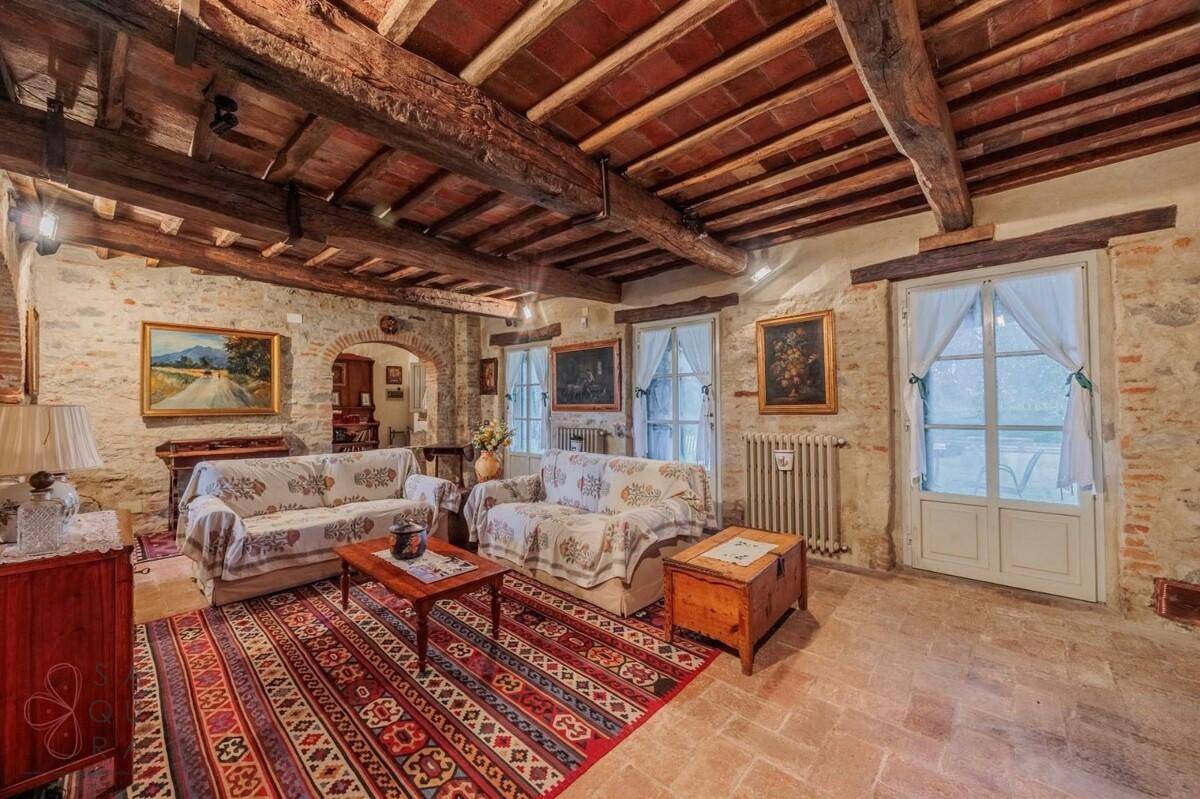 Gemütliches Wohnzimmer mit zwei Sofas, Holzbalkendecke und traditioneller Einrichtung.