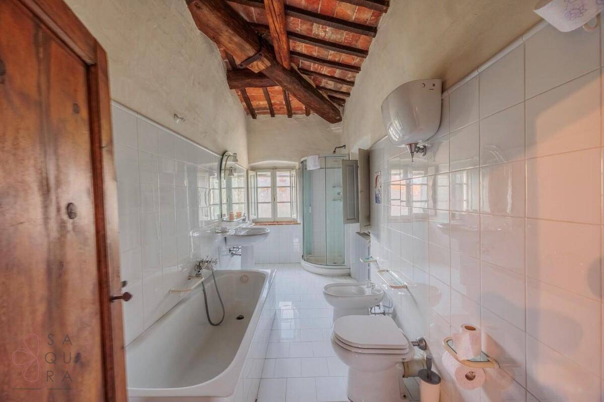 Badezimmer mit Badewanne, Duschkabine, Bidet und WC, gefliest mit weißen Fliesen und Holzbalkendecke.