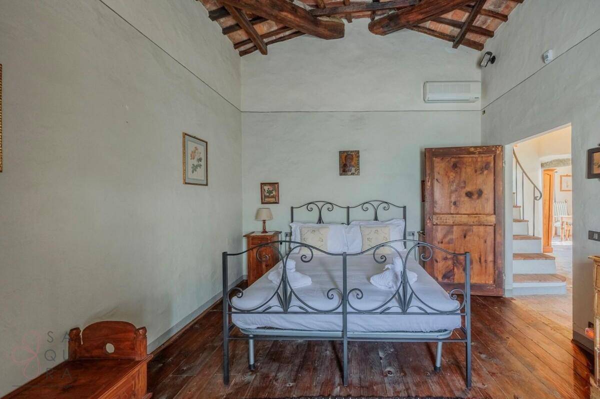 Schlafzimmer mit Holzbalkendecke, Holzboden und Klimaanlage, mit Zugang zu einem Flur und Treppenhaus.