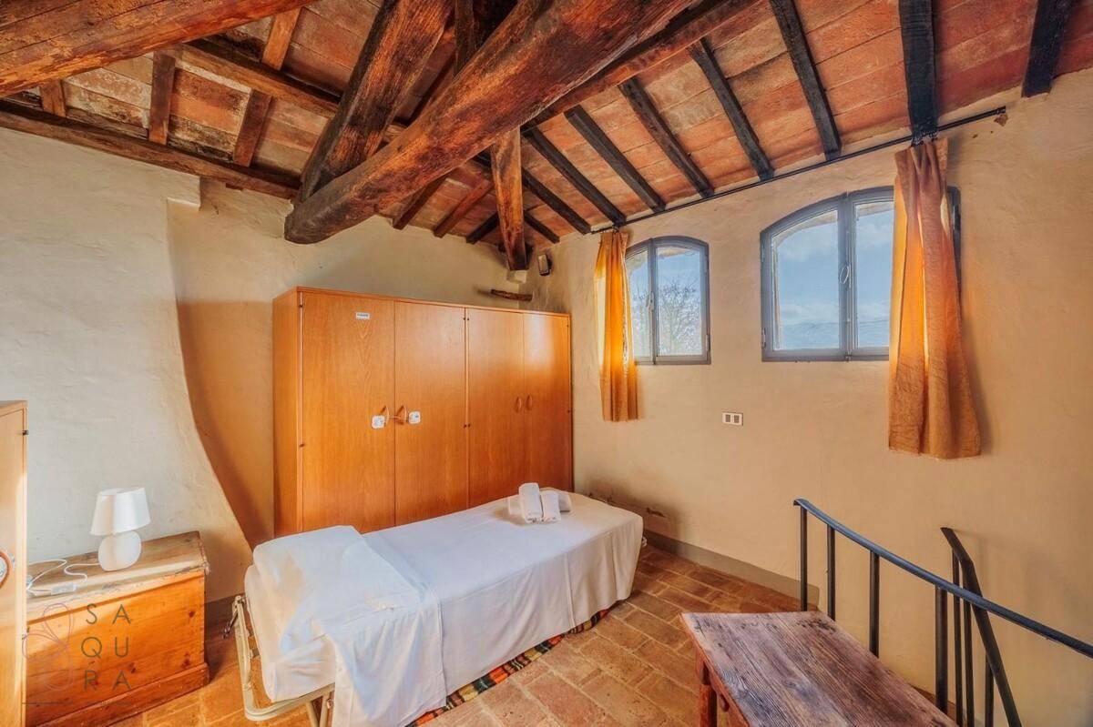 Kleines Schlafzimmer mit Holzbalkendecke, Terrakottaboden und Einbauschrank, ideal als Gästezimmer.