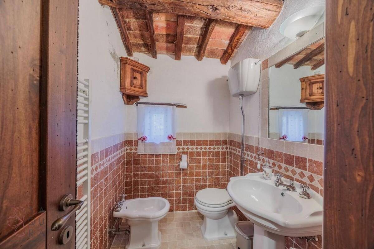 Gästetoilette mit Waschbecken, WC und Bidet, teilweise gefliest mit dekorativen braunen Fliesen.