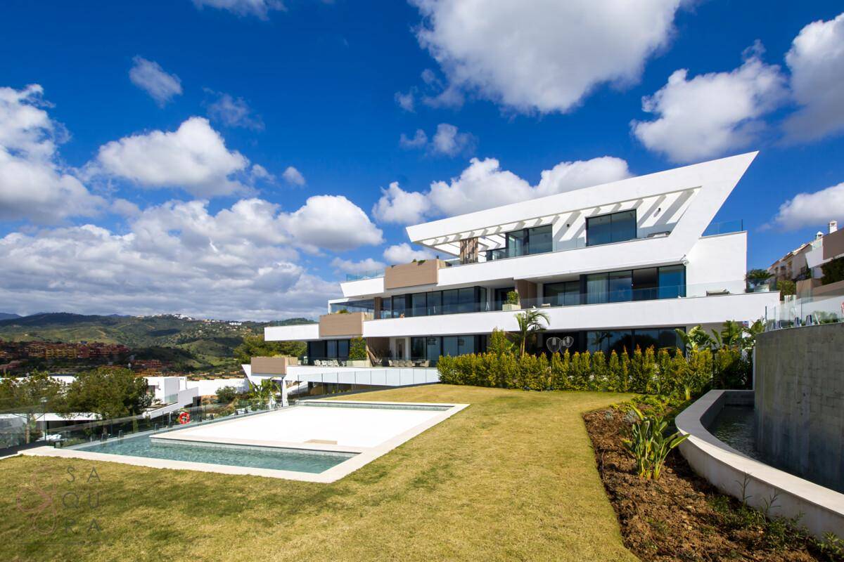 Moderner Wohnkomplex mit weitläufigen Grünflächen, Pool und Panoramablick auf die Berge.
