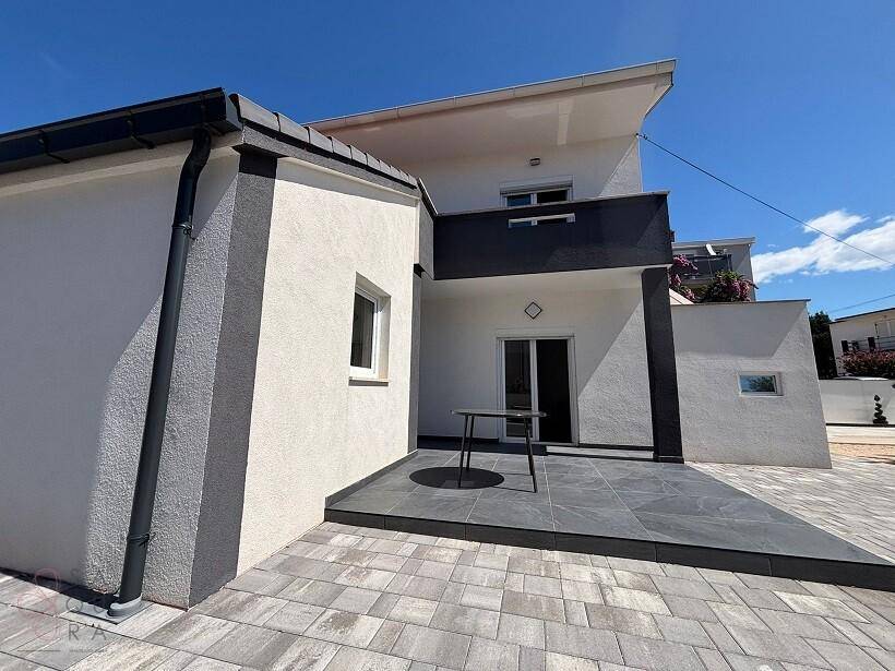 Kleine, moderne Terrasse mit dunklen Fliesen und einem Tisch, angrenzend an das Haus.