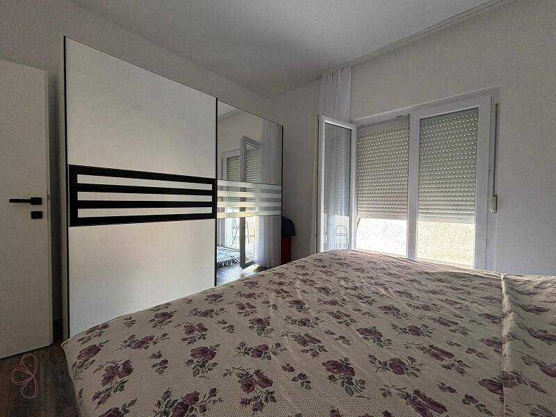 Schlafzimmer mit großem Kleiderschrank, Doppelbett und Zugang zu einem Balkon durch eine breite Tür.