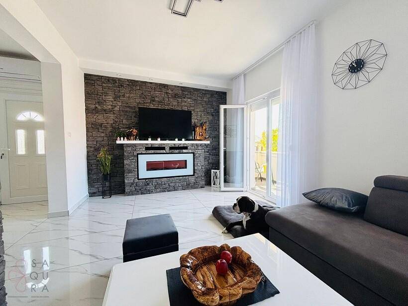 Helles Wohnzimmer mit modernen Fliesen, einem dekorativen Kamin und Zugang zu einem Balkon.